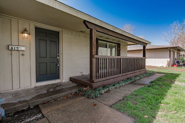 doorway to property with brick siding and covered porch