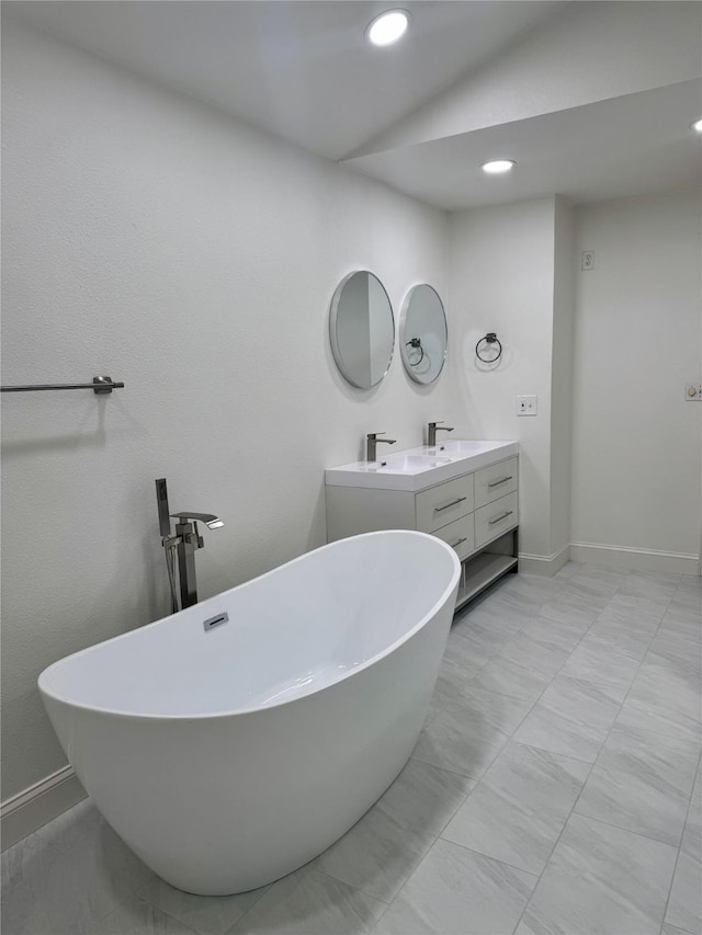 bathroom with double vanity, baseboards, recessed lighting, and a soaking tub