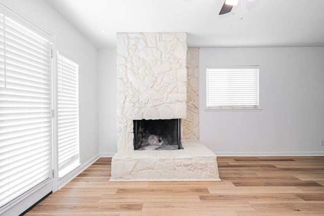 unfurnished living room featuring baseboards, a fireplace, a ceiling fan, and wood finished floors