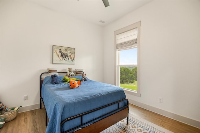 bedroom with baseboards, a ceiling fan, wood finished floors, and visible vents
