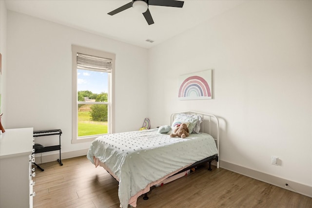 bedroom featuring baseboards, visible vents, ceiling fan, and light wood-style floors