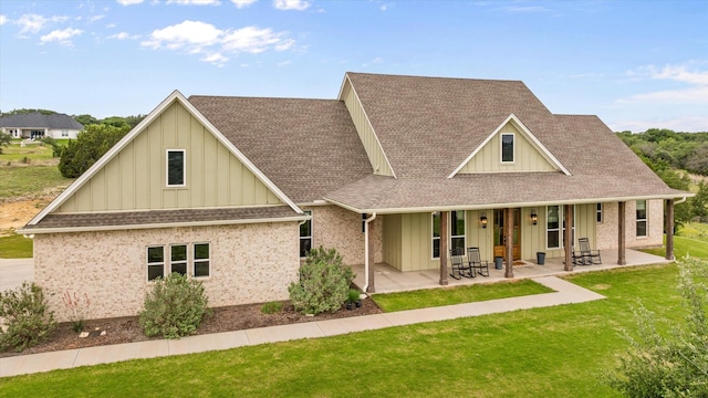 view of front of property featuring board and batten siding, roof with shingles, and a front lawn