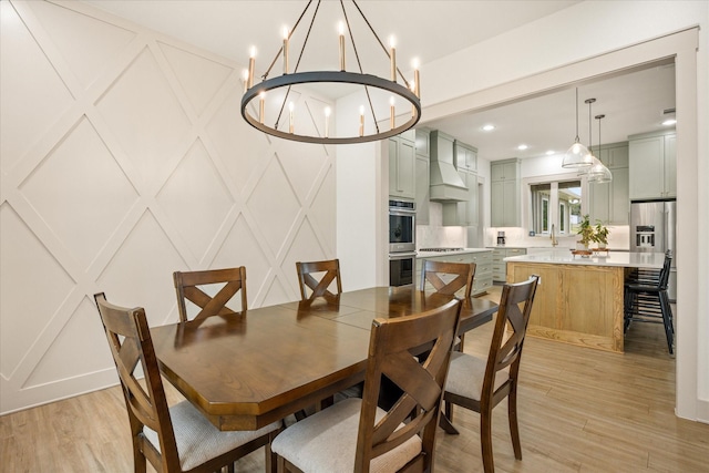 dining room featuring recessed lighting, an inviting chandelier, light wood-style flooring, and a decorative wall