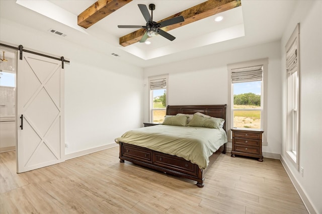 bedroom with visible vents, a barn door, multiple windows, and light wood-style floors