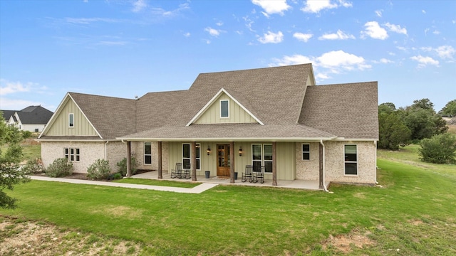 view of front of house with brick siding, board and batten siding, roof with shingles, and a front yard