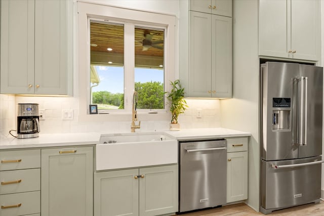 kitchen with light countertops, a sink, appliances with stainless steel finishes, and tasteful backsplash