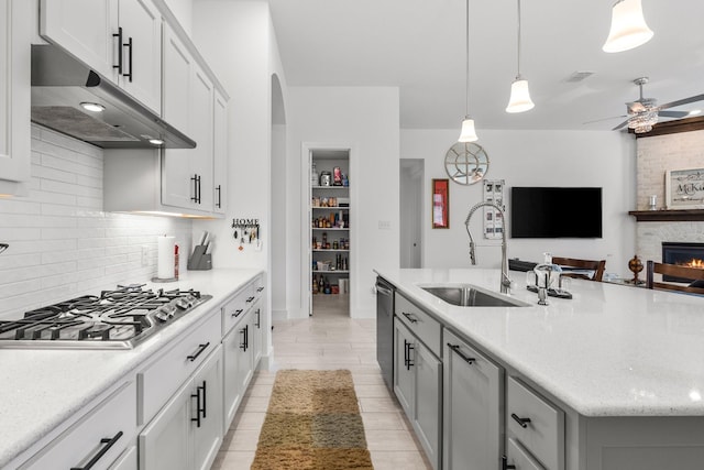 kitchen with ceiling fan, dishwasher, a sink, stainless steel gas stovetop, and under cabinet range hood