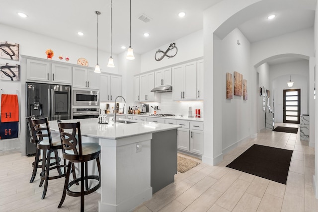 kitchen with a sink, light countertops, arched walkways, stainless steel appliances, and visible vents