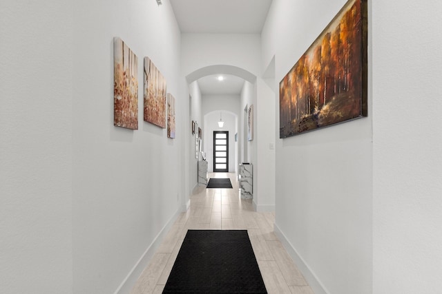 corridor featuring arched walkways and baseboards