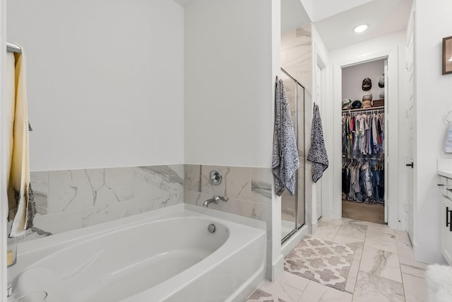 bathroom featuring marble finish floor, recessed lighting, a shower stall, a spacious closet, and a bath