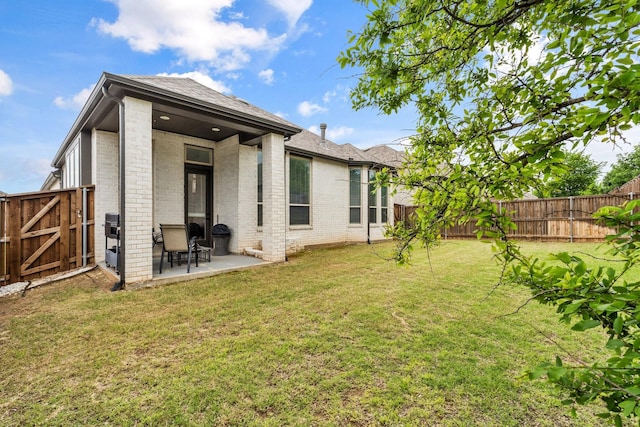 back of house featuring brick siding, a fenced backyard, a gate, and a patio