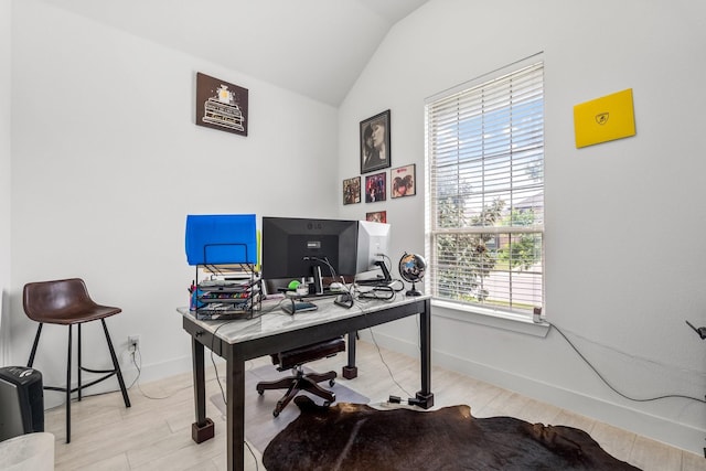 office space with plenty of natural light, baseboards, lofted ceiling, and light wood-type flooring
