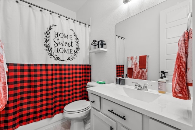 full bath with vanity, a textured wall, and toilet