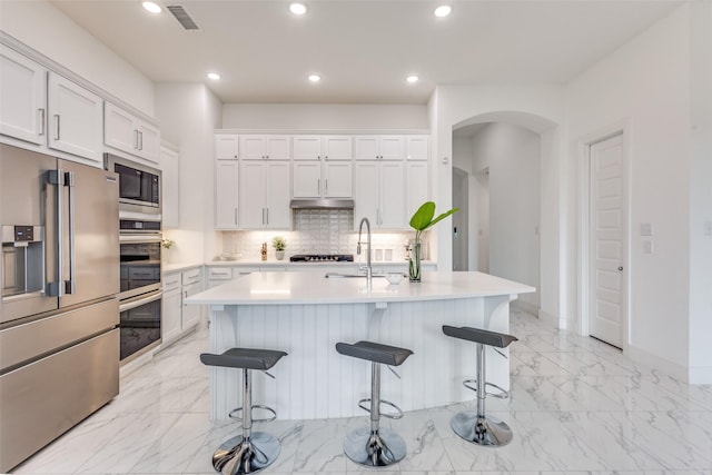 4012 Prickly Pear Ave, Aubrey, TX 76227 - kitchen with a kitchen breakfast bar, visible vents, appliances with stainless steel finishes, arched walkways, and marble finish floor