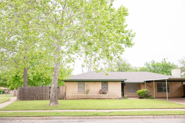 ranch-style home with a chimney, fence, a front yard, and a carport