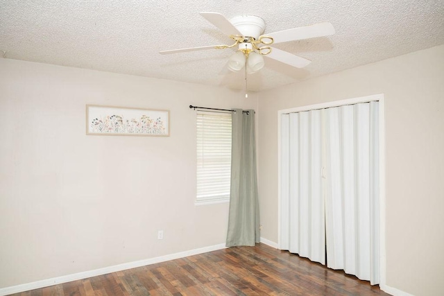 unfurnished room with baseboards, a ceiling fan, dark wood finished floors, and a textured ceiling