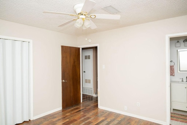 unfurnished bedroom with a textured ceiling, baseboards, wood finished floors, visible vents, and a closet