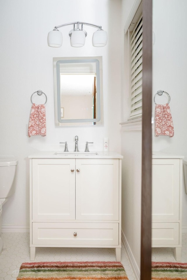bathroom with vanity, baseboards, and toilet