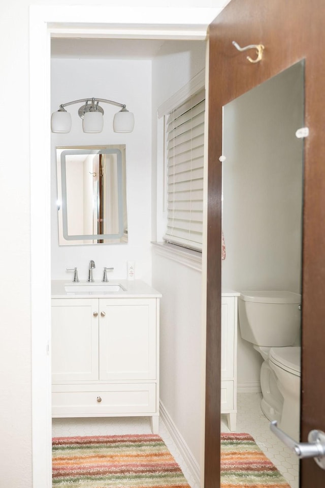 bathroom featuring vanity, tile patterned floors, baseboards, and toilet