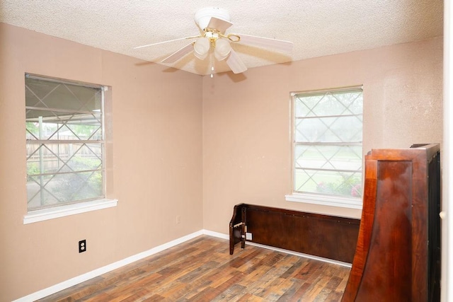 spare room with a textured ceiling, plenty of natural light, and wood finished floors