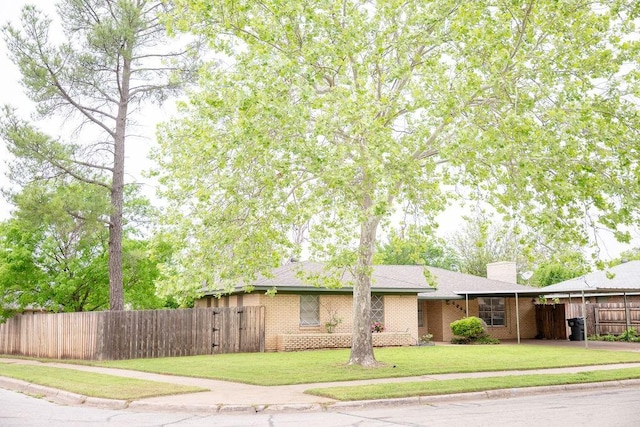 ranch-style house with brick siding, fence, a chimney, and a front yard