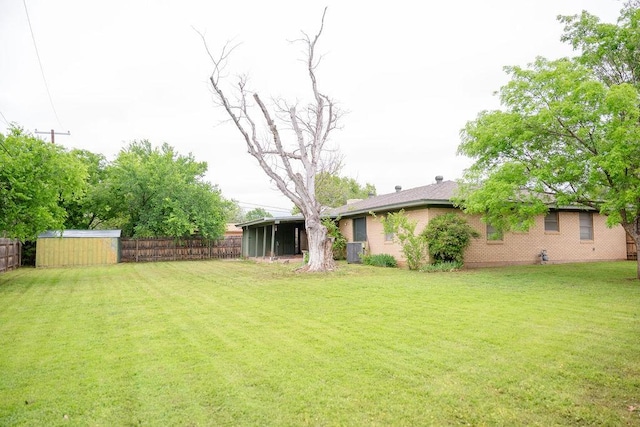 view of yard with a fenced backyard, a storage unit, an outdoor structure, and a sunroom