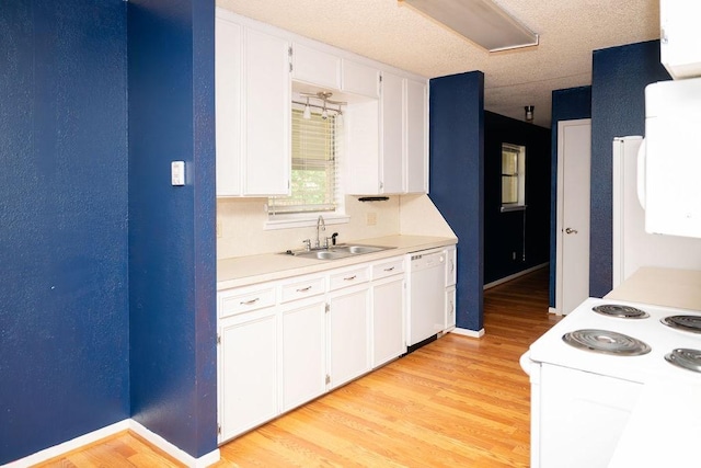 kitchen featuring white appliances, light countertops, white cabinets, a sink, and light wood finished floors