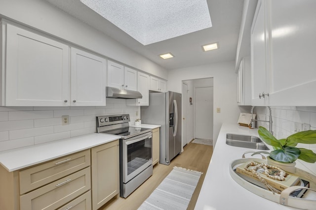 kitchen featuring decorative backsplash, light wood-style floors, light countertops, under cabinet range hood, and stainless steel appliances
