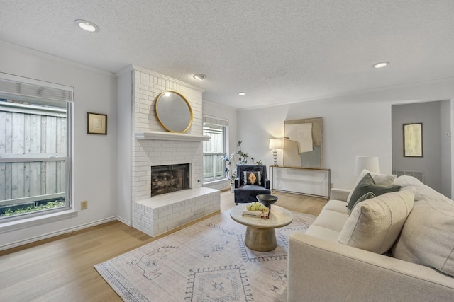 living area with crown molding, a textured ceiling, wood finished floors, and a fireplace