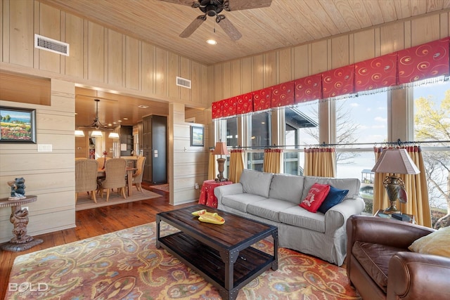 living area featuring wooden walls, visible vents, wood ceiling, and wood finished floors