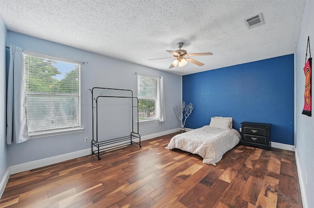 bedroom featuring visible vents, a textured ceiling, wood finished floors, and multiple windows