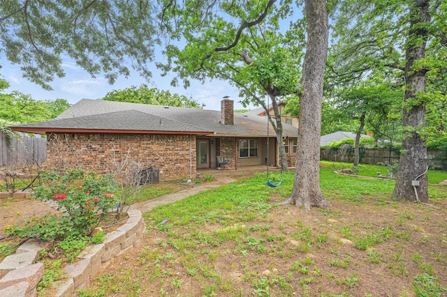 rear view of property with roof with shingles, fence, a yard, and a chimney