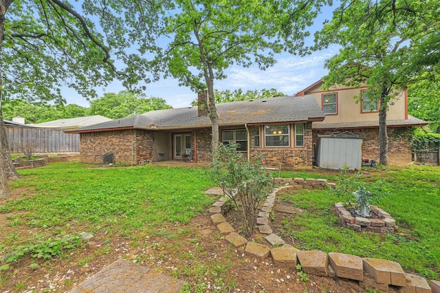 back of house featuring a lawn, fence, and an outdoor fire pit