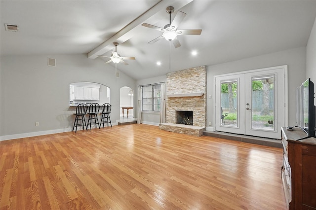 unfurnished living room featuring arched walkways, vaulted ceiling with beams, light wood finished floors, and visible vents