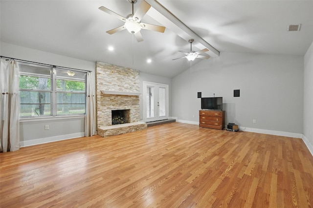 unfurnished living room with ceiling fan, a stone fireplace, baseboards, lofted ceiling with beams, and light wood finished floors