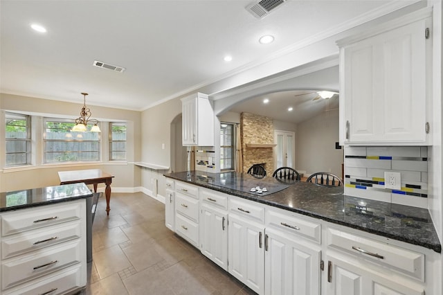 kitchen featuring backsplash, arched walkways, white cabinets, and visible vents