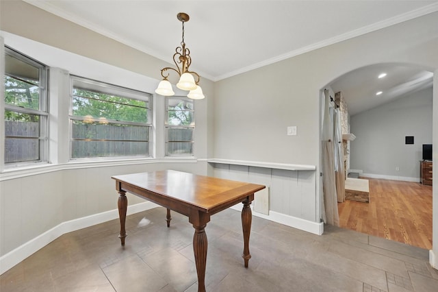 dining room with arched walkways, baseboards, ornamental molding, and a wealth of natural light