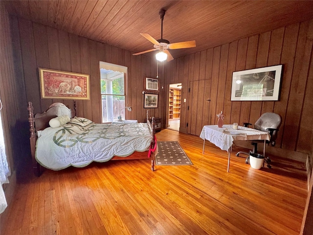 900 Park Dr, Hillsboro, TX 76645 - bedroom with wooden walls, an AC wall unit, access to exterior, and hardwood / wood-style floors