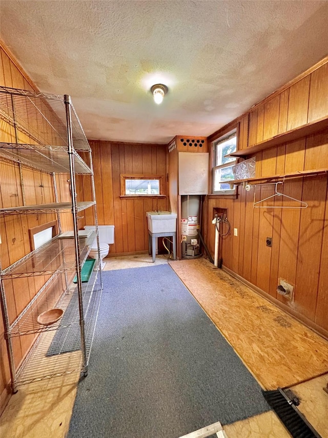 900 Park Dr, Hillsboro, TX 76645 - basement featuring a textured ceiling, wood walls, a sink, water heater, and carpet flooring