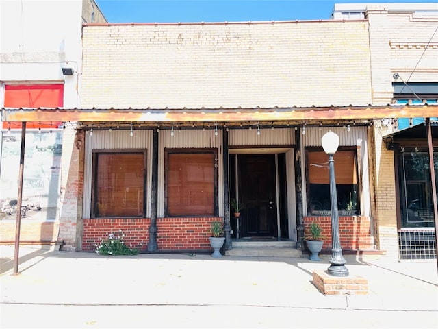 property entrance with a porch and brick siding