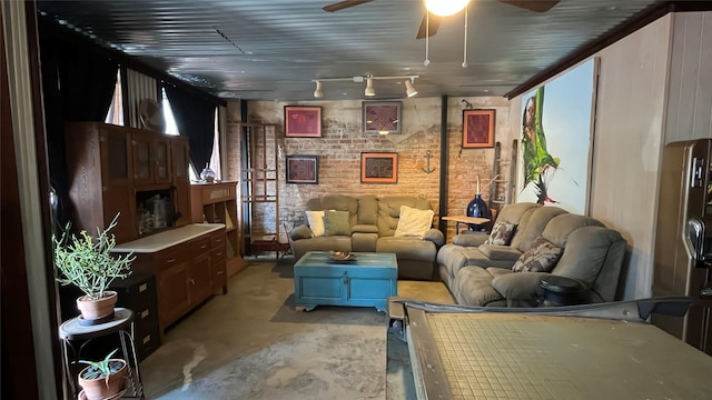 living room with a ceiling fan, brick wall, and unfinished concrete flooring