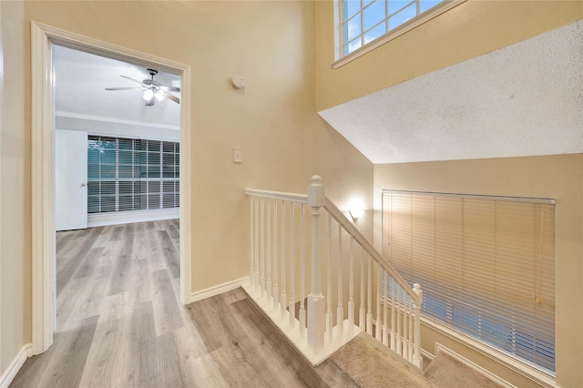 stairway featuring baseboards, a ceiling fan, and wood finished floors