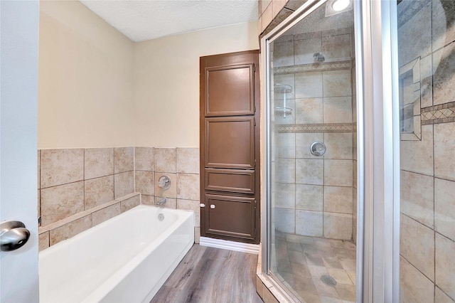 bathroom featuring wood finished floors, a stall shower, and a bath