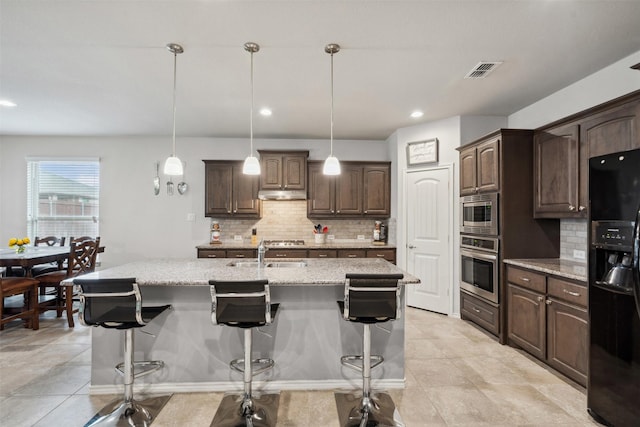 kitchen with a sink, a breakfast bar area, stainless steel appliances, tasteful backsplash, and visible vents