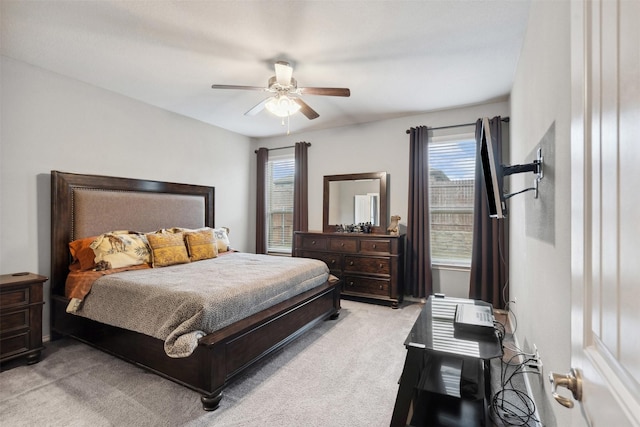 bedroom with ceiling fan, light carpet, and multiple windows