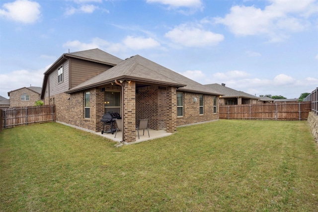 rear view of house with a fenced backyard, a yard, a patio area, and brick siding