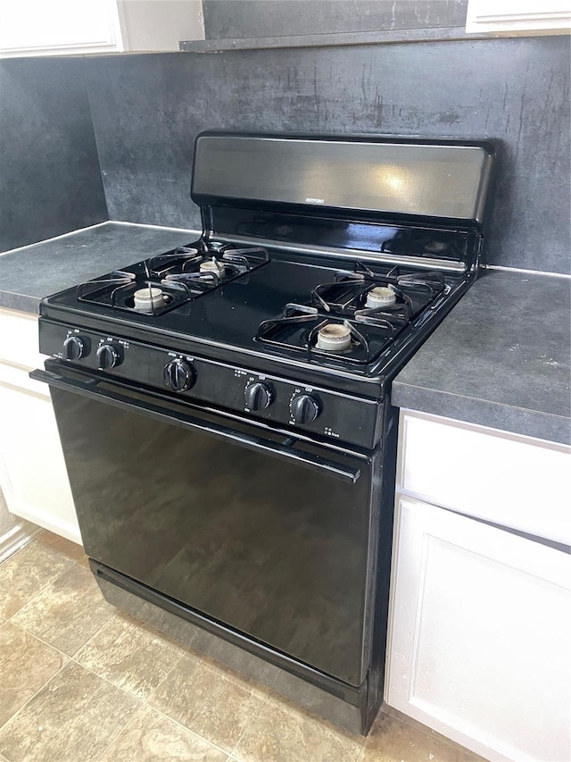 details featuring black range with gas cooktop, dark countertops, and white cabinetry