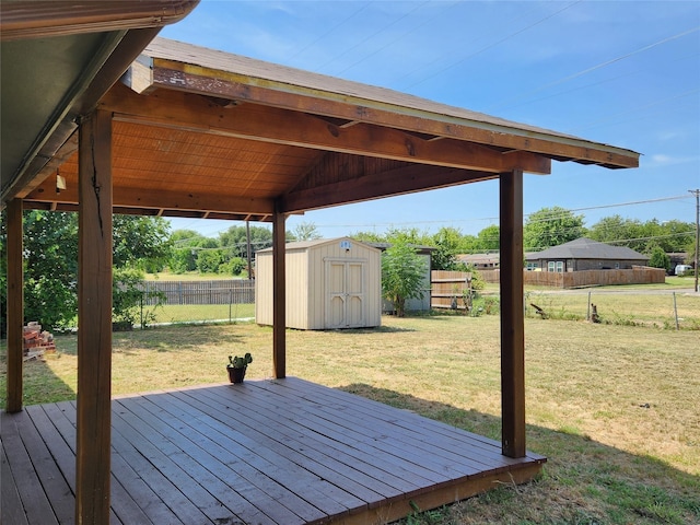 wooden deck featuring a storage shed, an outdoor structure, a yard, and a fenced backyard