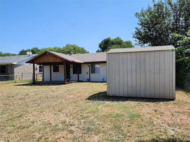 rear view of house with fence, an outdoor structure, a yard, and a storage shed