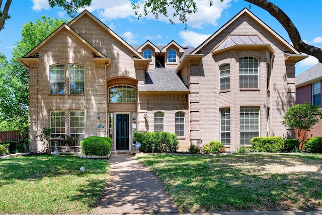 view of front of house with brick siding, roof with shingles, and a front lawn